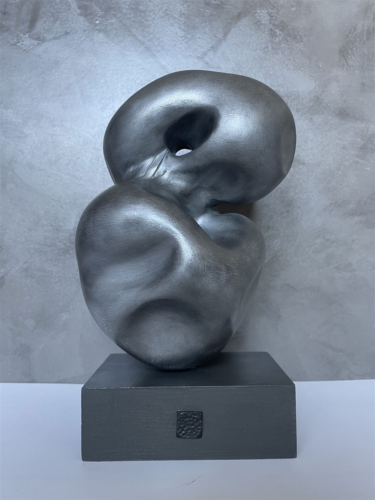 Conflux — silver-toned abstract sculpture of two folded, interlocking forms